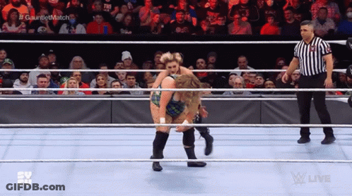Two Women Are Wrestling In A Ring While A Referee Watches . GIF