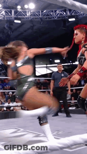 Two Women Are Wrestling In A Ring While A Referee Watches GIF