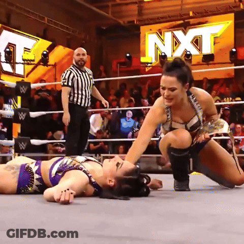 Two Women Are Wrestling In A Ring With A Sign That Says Nxt On It GIF