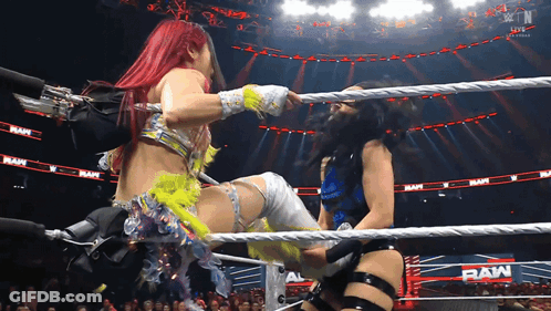 Two Women Are Wrestling In A Ring With The Word Raw On The Walls GIF
