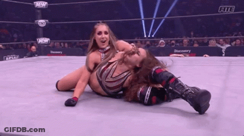 Two Women Are Wrestling In A Wrestling Ring And One Of Them Is Laying On The Ground . GIF