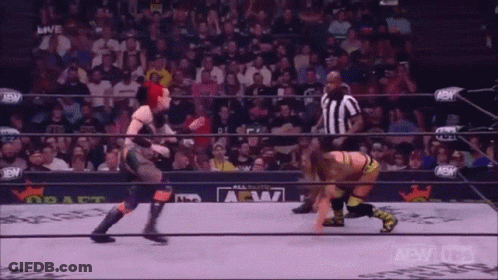 Two Women Are Wrestling In A Wrestling Ring With A Referee In The Background . GIF