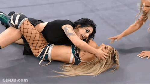 Two Women Are Wrestling On A Wrestling Mat With The Letters N On The Bottom Right GIF