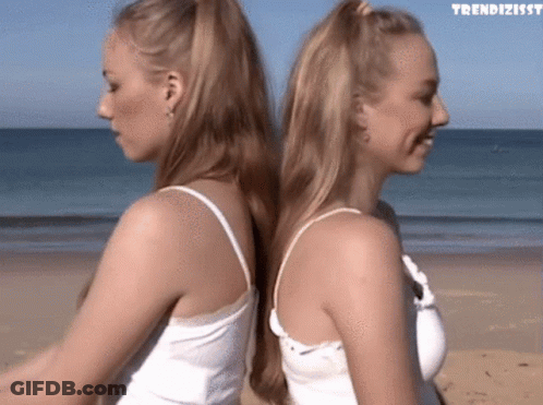 Two Women Back To Back On Beach With Trendizissy GIF