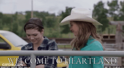 Two Women Behind Fence Saying Welcome To Heartland GIF