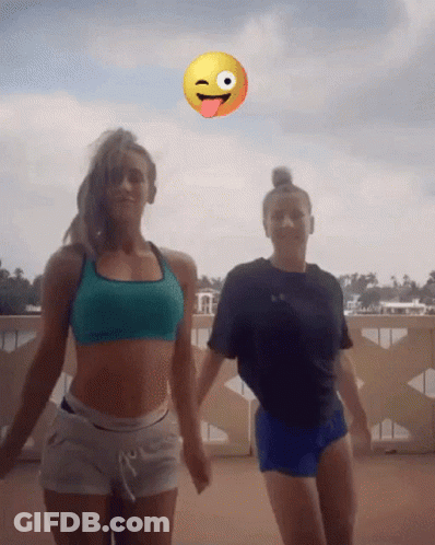 Two Women Dancing Before Smiley Face Sticking Tongue Out GIF