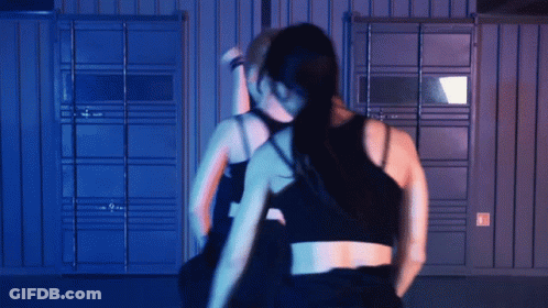 Two Women Dancing In Dark Room With Blue Wall GIF