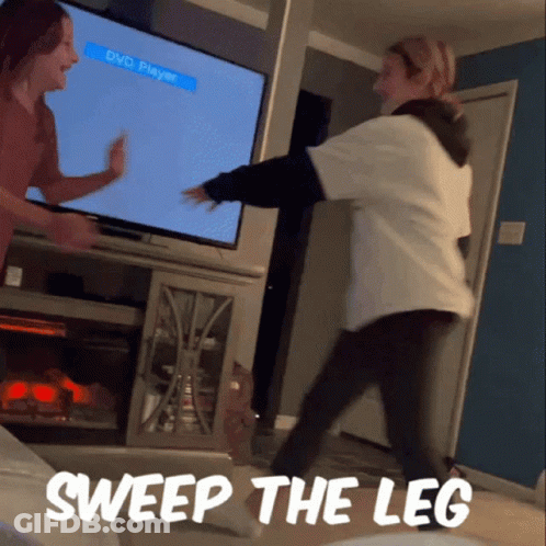 Two Women Dancing In Front Of A Tv With The Words Sweep The Leg GIF