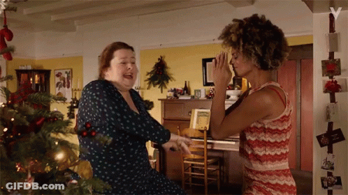 Two Women Dancing In Front Of Christmas Tree GIF