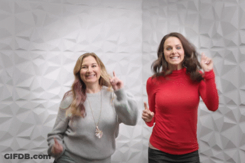 Two Women Dancing In Front Of White Wall One In Red Shirt GIF