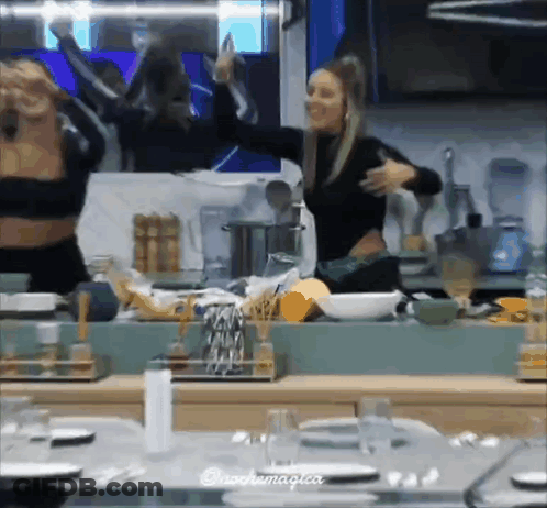 Two Women Dancing In Kitchen In Front Of Mirror GIF
