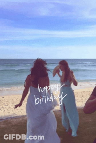 Two Women Dancing On A Beach With The Words Happy Birthday Written On The Beach GIF
