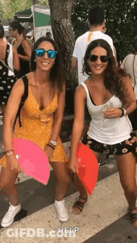 Two Women Holding Fans On Sidewalk GIF