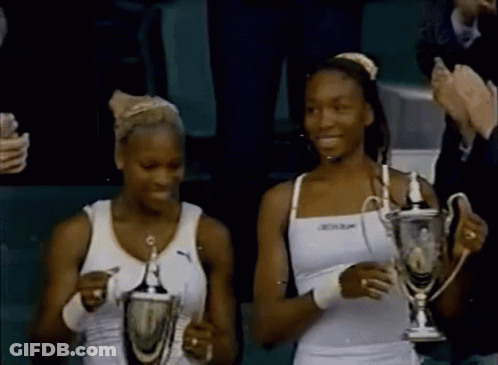 Two Women Holding Trophies With Dunlop On Top GIF