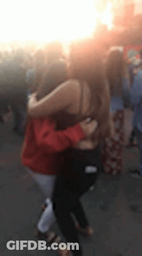 Two Women Hugging In Blurry Crowd GIF