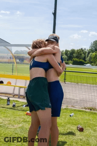 Two Women Hugging In Field With Water Bottle GIF