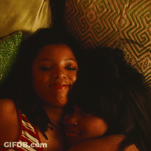 Two Women Hugging On Bed With Patterned Pillow GIF
