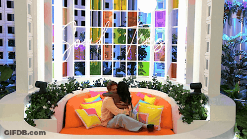 Two Women Hugging On Couch By Stained Glass Window GIF