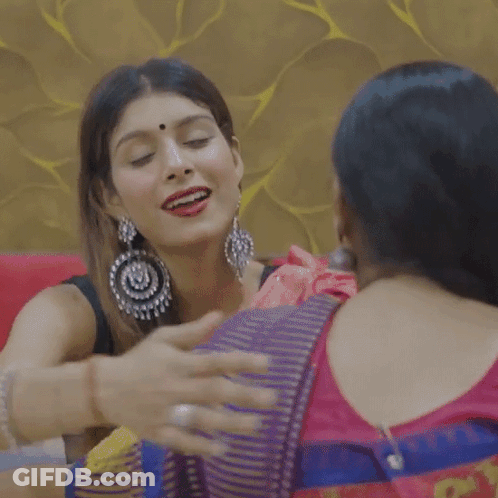 Two Women Hugging On Couch One Wearing Earrings GIF