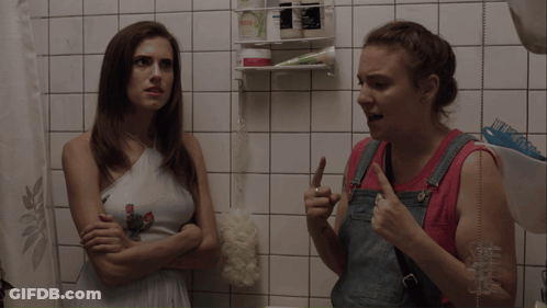 Two Women In Bathroom One Holding Shampoo GIF