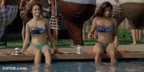 Two Women In Bikinis Are Sitting In A Swimming Pool GIF