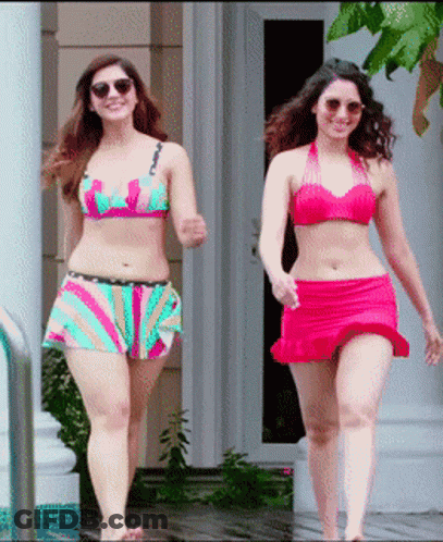 Two Women In Bikinis Are Walking In Front Of A House GIF