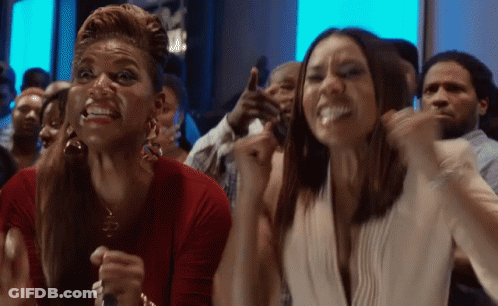 Two Women In Crowd Arms Up Making Funny Faces GIF
