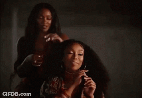 Two Women In Dark Room One Holding Hair GIF