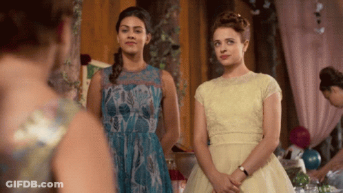 Two Women In Dresses Are Standing Next To Each Other In A Room GIF