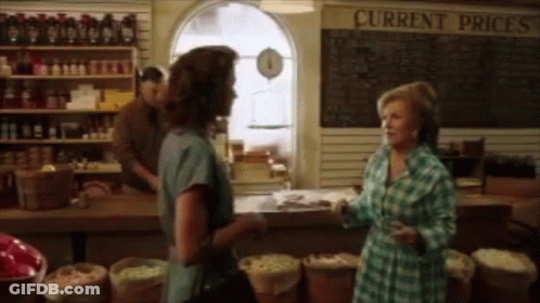 Two Women In Front Of Current Prices Sign GIF