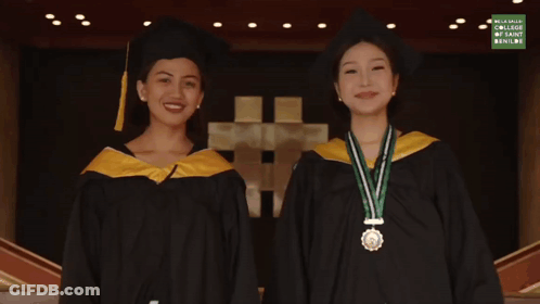 Two Women In Graduation Gowns Next To Palawulang Sign GIF