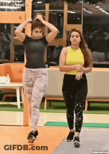 Two Women In Gym One Adjusting Hair GIF