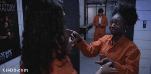 Two Women In Orange Jumpsuits In Front Of Laboratory Poster GIF