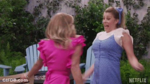 Two Women In Pink And Blue Dresses Are Dancing In Front Of Blue Chairs And A Netflix Logo GIF