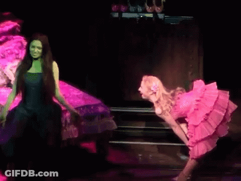 Two Women In Pink And Green Dresses On Stage GIF