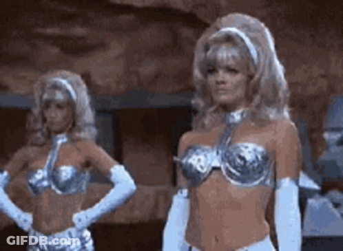 Two Women In Silver Bikinis And White Gloves In Cave GIF