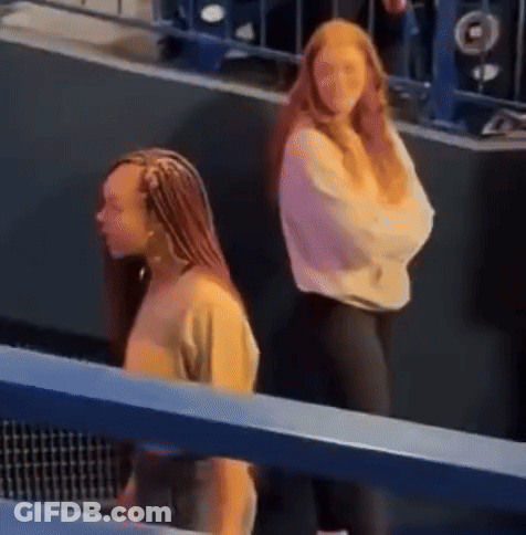 Two Women In Stadium, One With Braids GIF