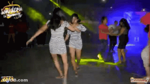 Two Women In Striped Dresses Are Dancing On A Dance Floor In A Club . GIF