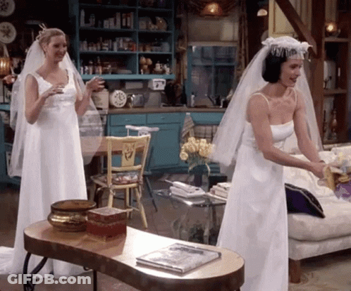 Two Women In Wedding Dresses Standing Next To Each Other GIF