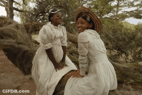 Two Women In White Dresses Sitting Next To Each Other GIF