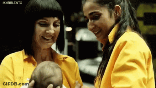Two Women In Yellow Shirts Are Holding A Baby . GIF