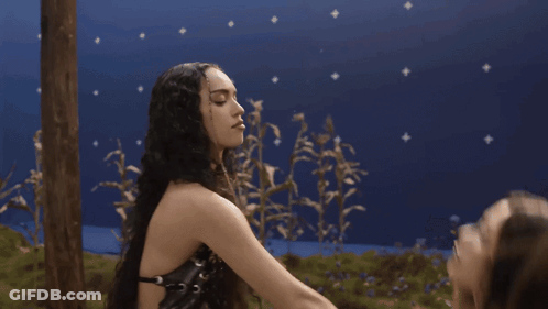 Two Women Kissing Each Other In Front Of A Blue Background GIF