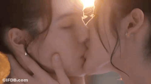 Two Women Kissing In Front Of Light Bulb GIF