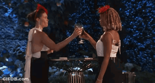 Two Women Kissing While Drinking From Glasses GIF