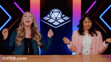 Two Women Laughing With Arms In Air At Table GIF