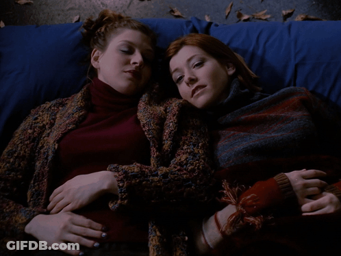 Two Women Laying Next To Each Other With Teach Me GIF