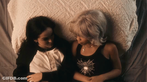 Two Women Laying On Bed, One With Spider Web Tank Top GIF