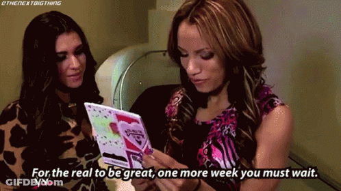 Two Women Looking At Card Saying For The Real To Be Great One More Week You Must Wait GIF