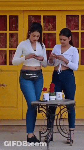 Two Women Looking At Phones With Adventure Awaits Fanny Pack GIF