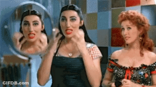 Two Women Looking At Themselves In Mirror GIF
